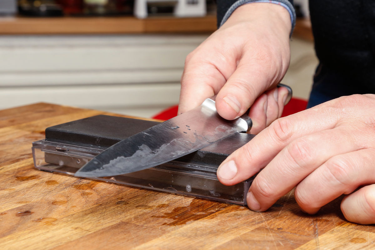 Close-up of a knife edge being professionally sharpened on a whetstone